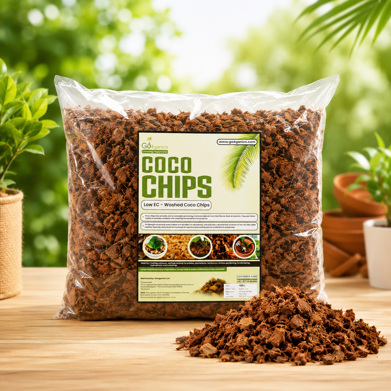 ag of Coco Chips (washed coco coir) sits on a wooden table with a pile of the brown coir chips in front. The background is a soft-focus green garden with potted plants.